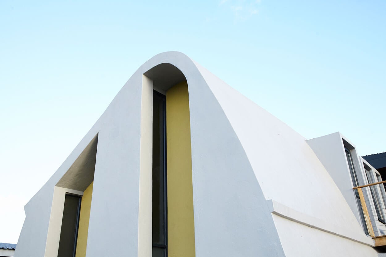 Modern minimalist building with curved white facade and yellow accents.
