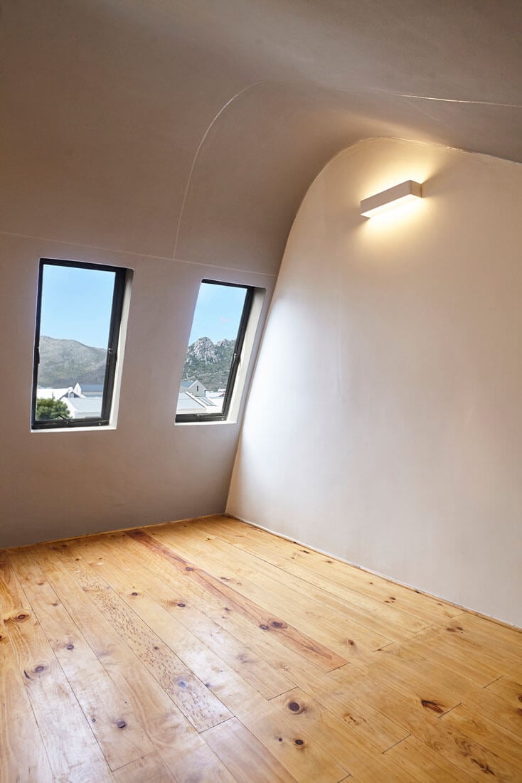 Attic room featuring two skylight windows, wooden flooring, and a sleek wall-mounted light fixture.