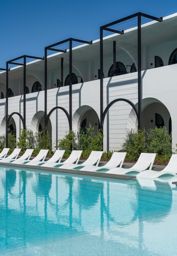 Modern luxury hotel with a swimming pool and stylish architecture in a sunny outdoor setting.