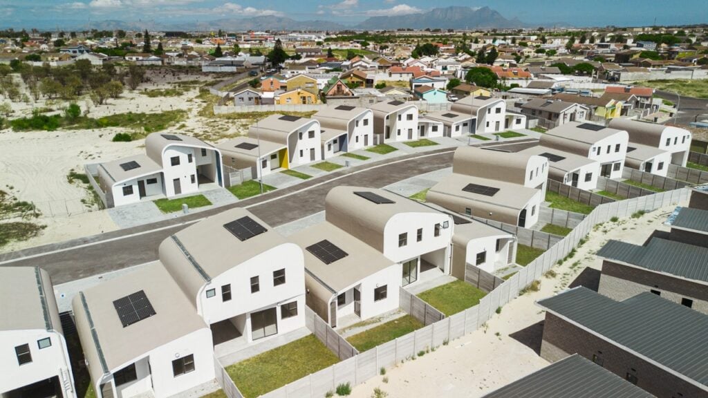 Modern residential housing development with white houses and solar panels in a suburban area.