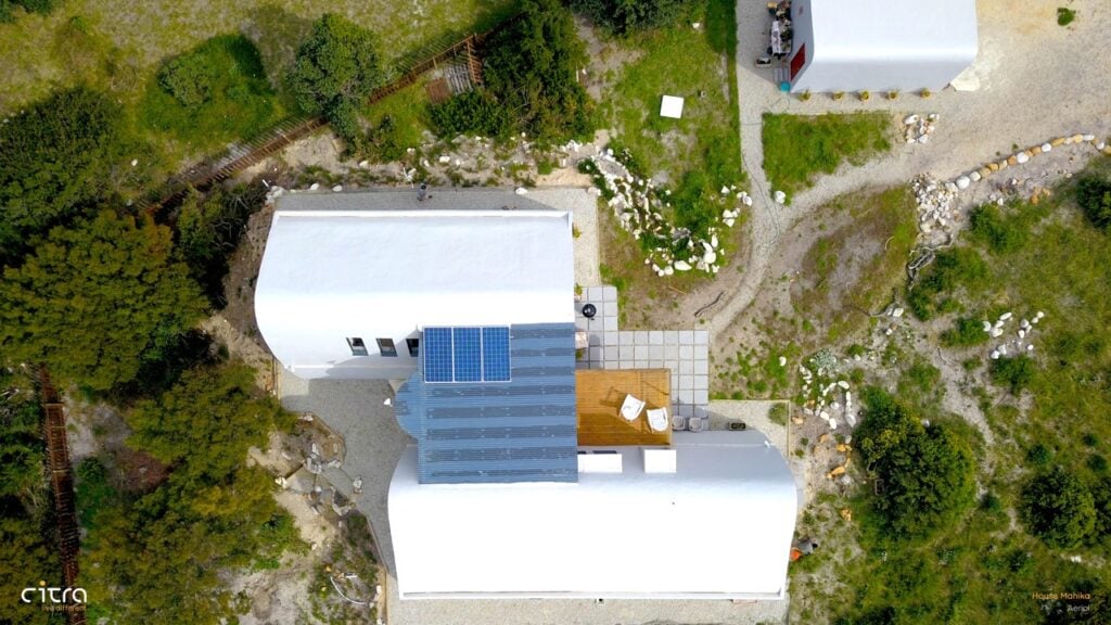 Solar-powered modern house with white exterior and rooftop solar panels in a lush green environment.