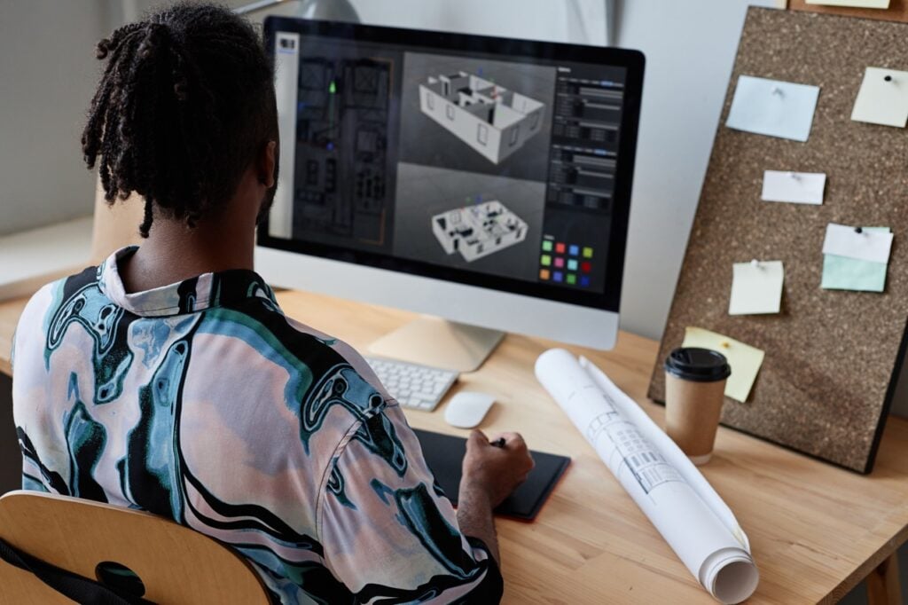 Modern interior designer working on 3D architectural plans on a desktop computer.