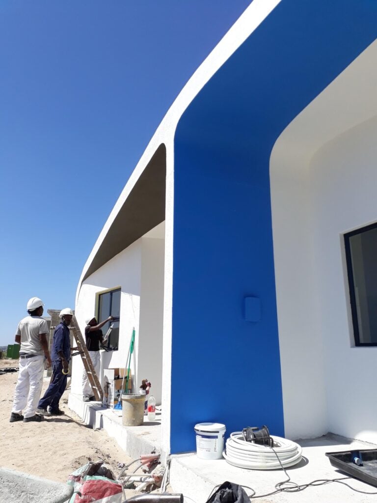 Modern residential building with white and blue exterior walls, under construction.