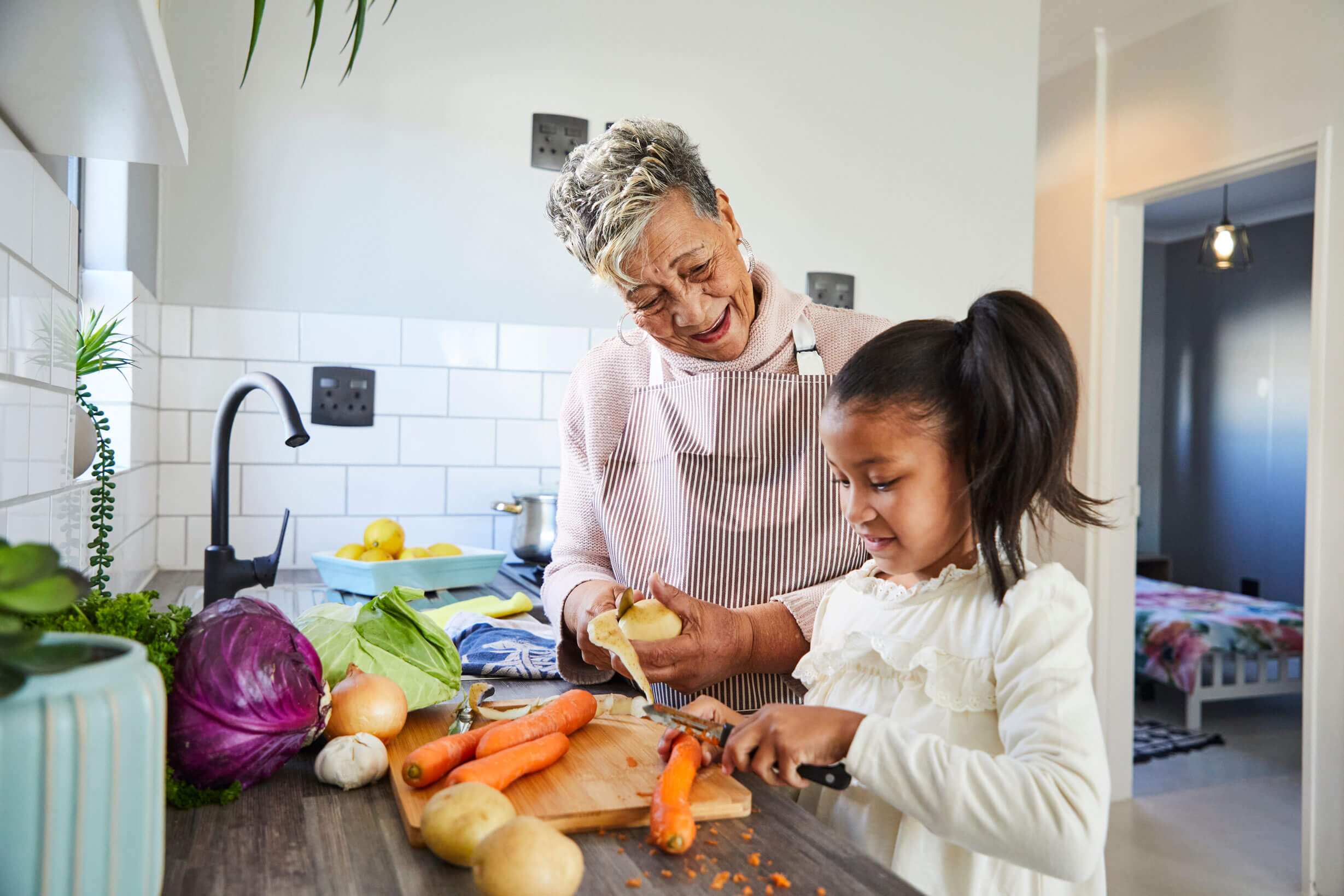 Social Impact Fresh vegetables and a joyful grandmother and granddaughter preparing a healthy meal in a modern kit.