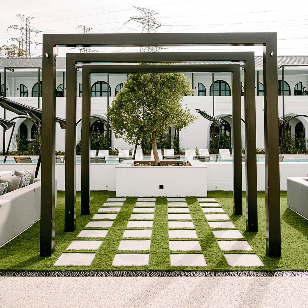 Contemporary outdoor pergola with a central tree and modern seating in an urban setting.