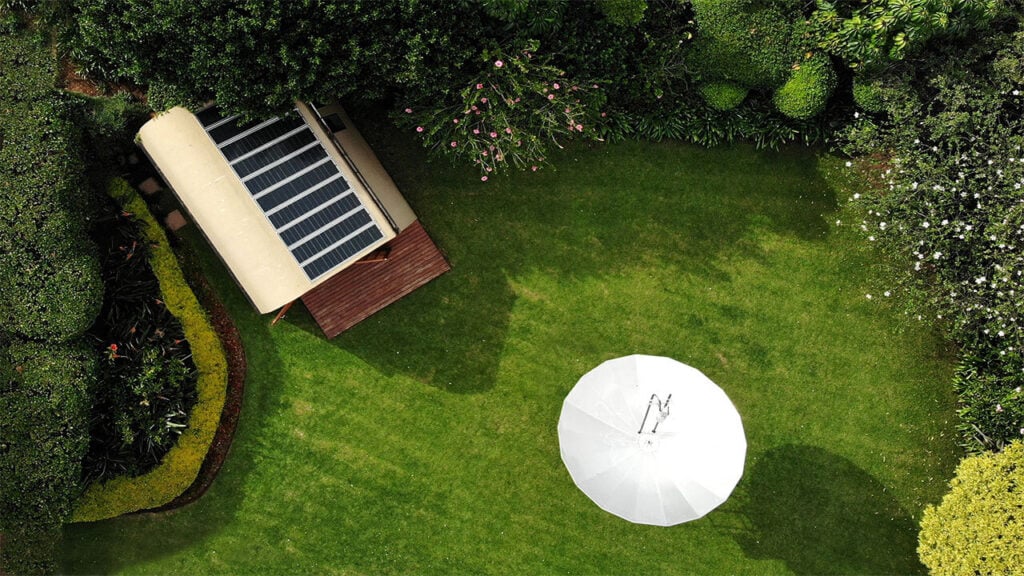 Solar-powered garden shed with lush greenery and outdoor seating area.