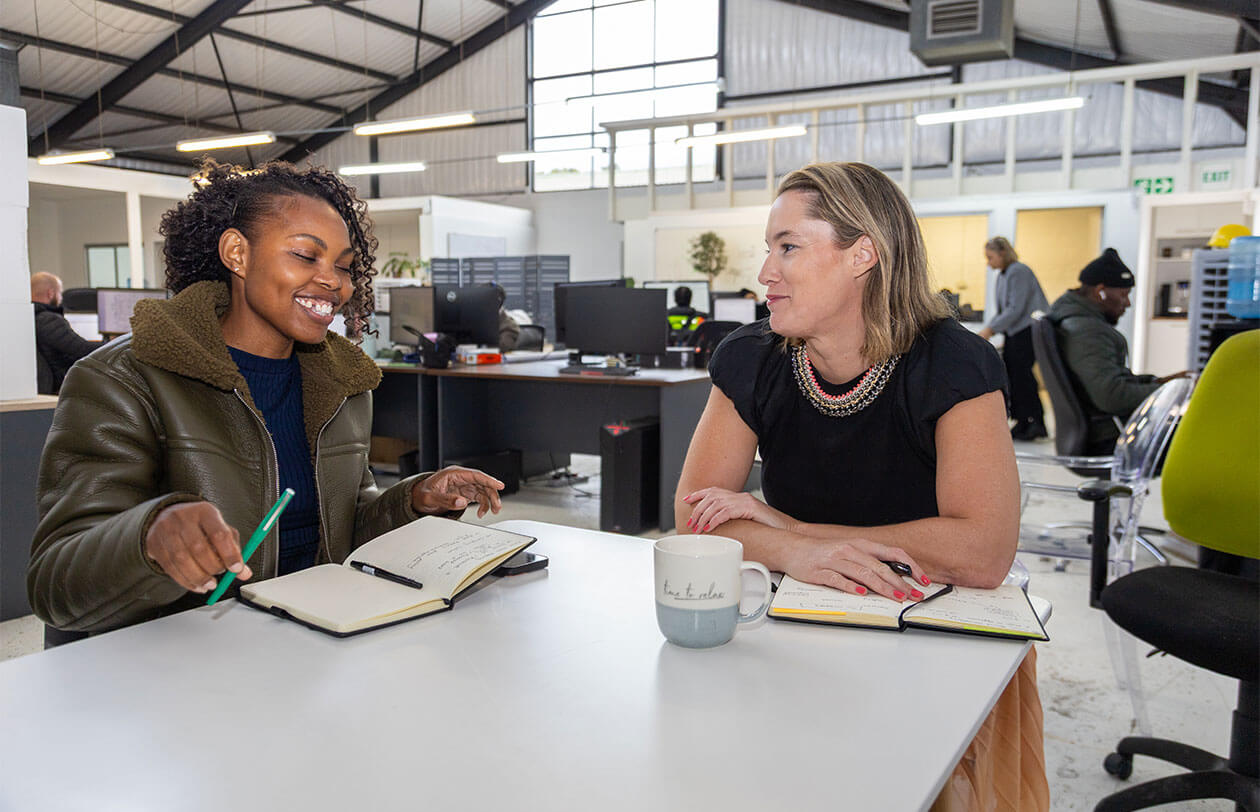 Careers Two women collaborating and discussing ideas in a contemporary office environment.