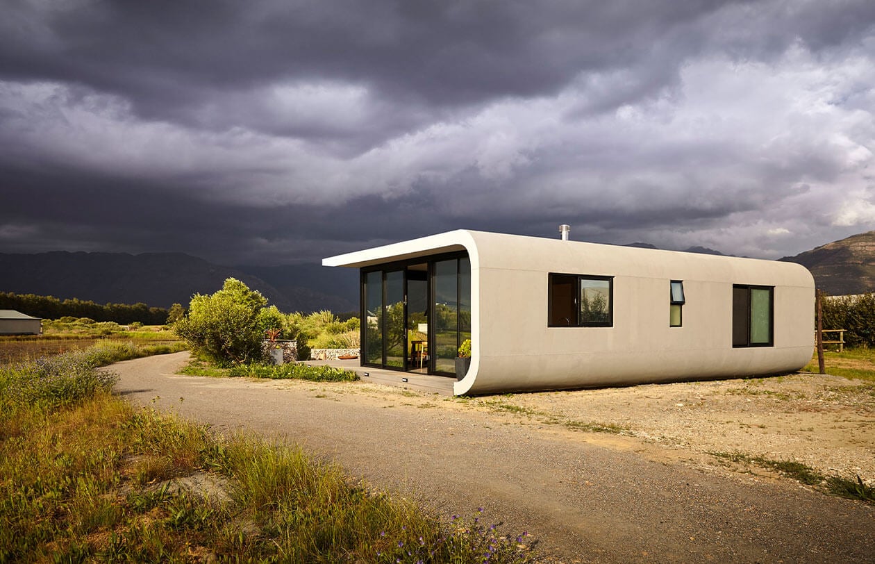 ePod Modern minimalist tiny house with curved design and large glass windows in a rural setting.