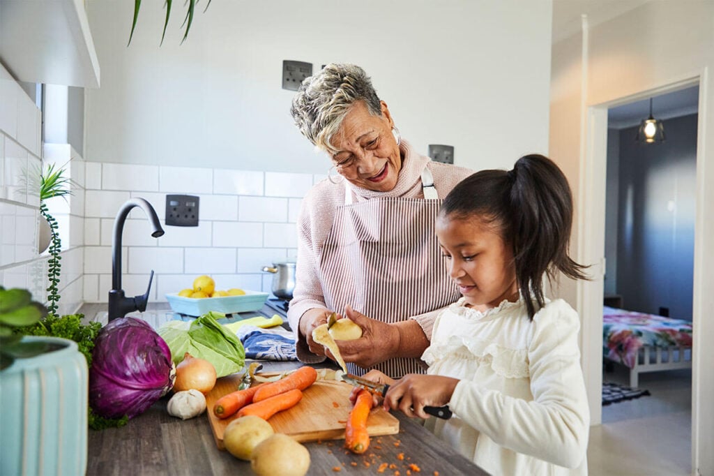Grandmother and granddaughter preparing vegetables together in a modern kitchen.