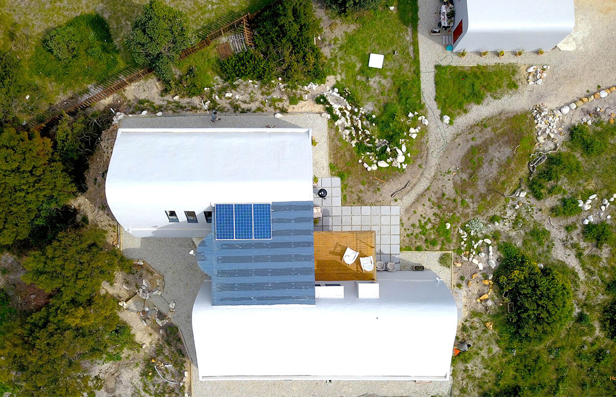 Sustainability Eco-friendly house with solar panels, white roof, and surrounding greenery in South Africa.