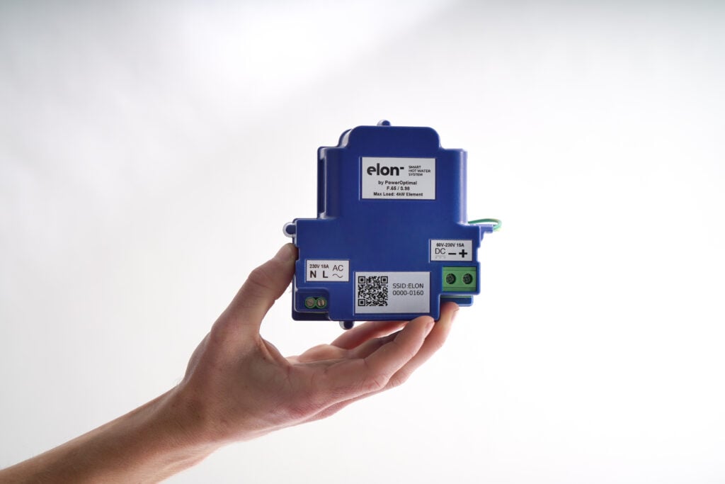 A hand holding a blue Elon Smart Hot Water System controller module against a bright white background.